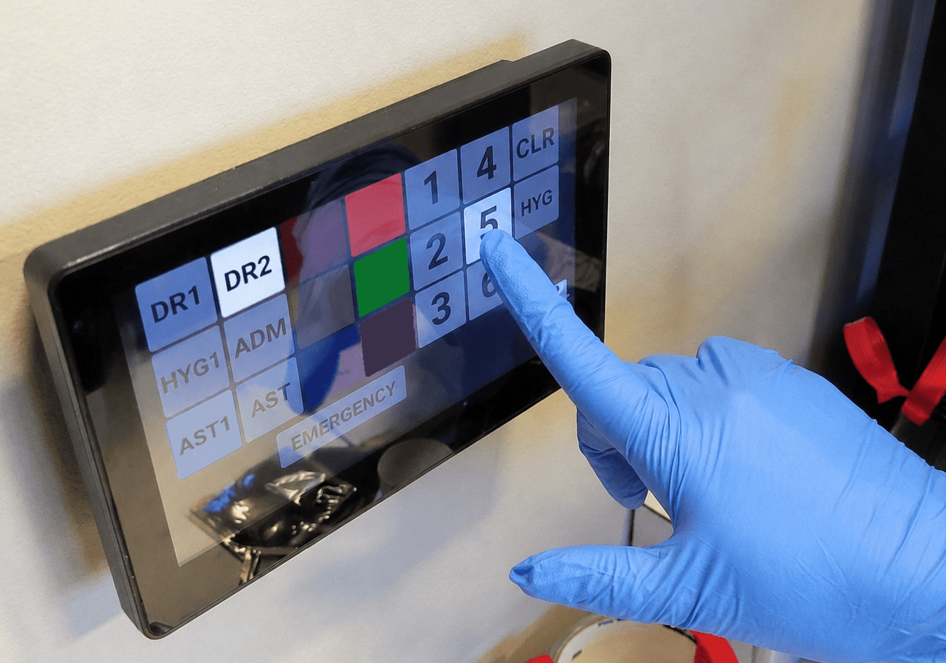 A gloved hand interacts with a touchscreen panel displaying various options, likely for monitoring or control in a medical or laboratory setting.